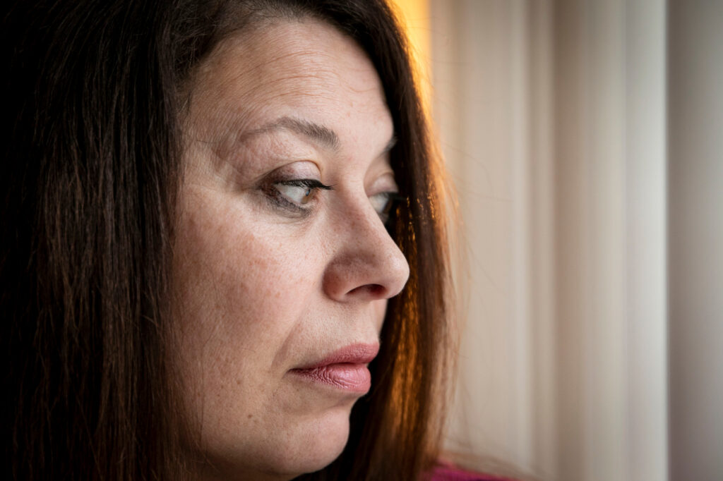 A closeup photo of a woman's face as she looks pensively to the side